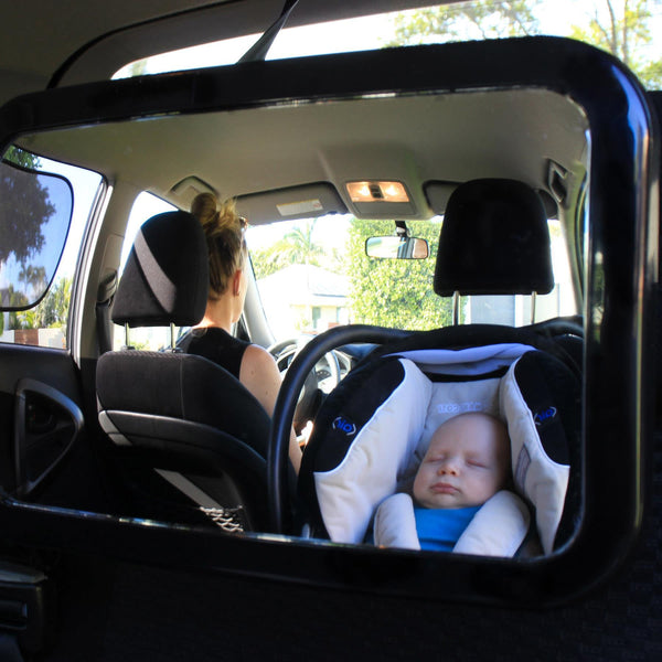 Rear-facing infant safely seated in a car, visible through the baby safety car mirror